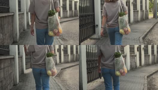女人带着网眼线编织的购物袋走在外面高清在线视频素材下载