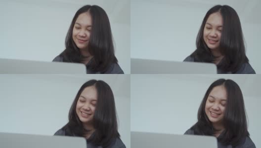 4k, Portrait，一个可爱的亚洲少女。穿着灰色衬衫，带着笔记本电脑在卧室的床上愉快地学习高清在线视频素材下载