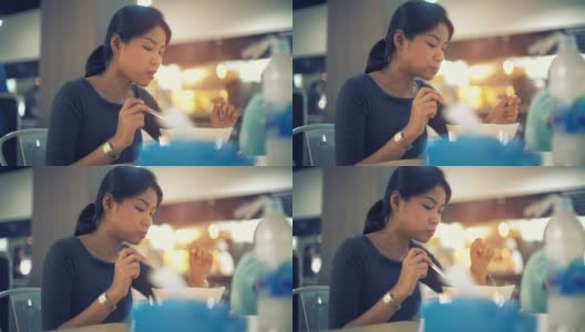 年轻的亚洲女士吃面汤在美食广场色调的视频高清在线视频素材下载
