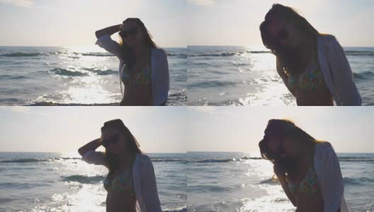 侧面美丽的女孩在比基尼和衬衫走在海边和玩她的头发。快乐的年轻女人戴着太阳镜，在暑假里享受生活。慢动作特写侧视图高清在线视频素材下载