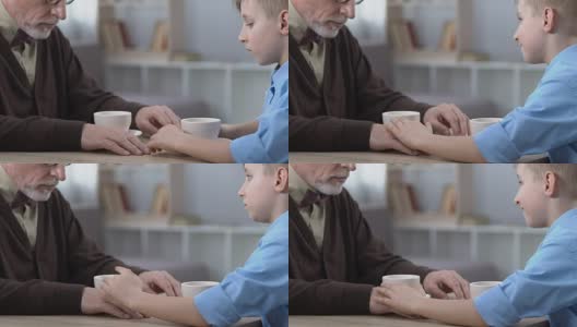 小男孩抚摸着伤心的爷爷的手，安慰他，家人的关心和帮助高清在线视频素材下载
