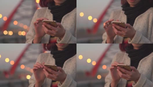 漂亮的年轻女孩在晚上使用智能手机在城市高清在线视频素材下载