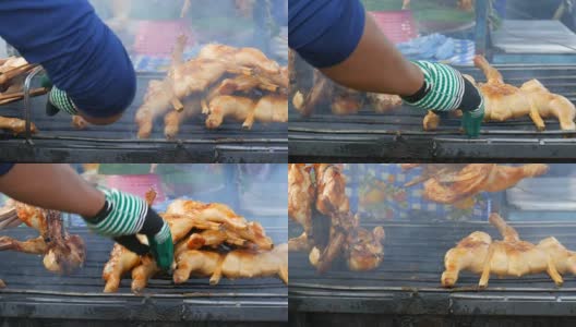 把整只鸡串在木棍上，放在烤架上烤制。泰国的街头食品。男人的手翻着烤鸡高清在线视频素材下载