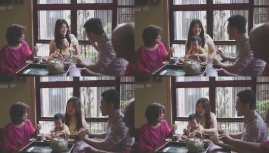 中国父亲与儿子在多代同堂期间享用传统的中秋节月饼和下午茶高清在线视频素材下载