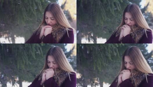 美丽的女孩用她的嘴温暖她的手在冬天的森林高清在线视频素材下载