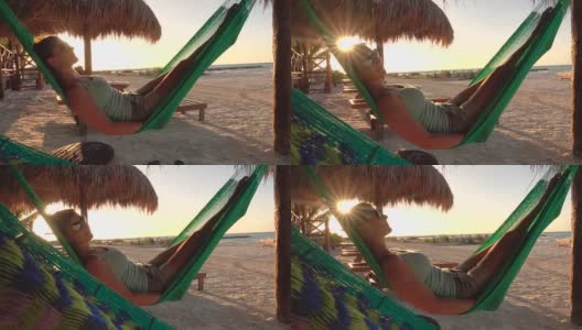 特写:女孩放松，荡秋千在吊床上俯瞰日落的沙滩高清在线视频素材下载