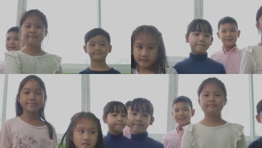 一群亚洲幼儿园的孩子正站在教室里。他们很高兴，对着镜头微笑。高清在线视频素材下载