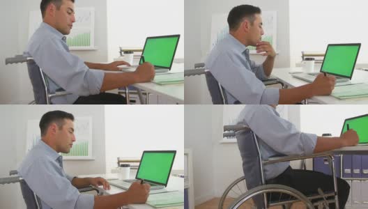 坐在轮椅上使用绿屏笔记本电脑的残疾商人高清在线视频素材下载