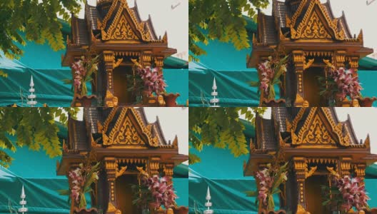 在一个花园里，棕色的佛坛供祈祷者使用，上面装饰着鲜花和各种小雕像高清在线视频素材下载