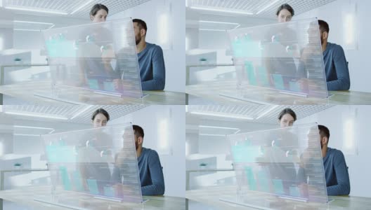 在不久的将来，男性和女性办公室工作人员讨论在透明电脑显示器上显示的图形统计。漂亮的人说话。屏幕上的交互式图表。高清在线视频素材下载