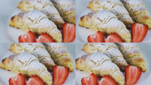 白砂糖和草莓片的甜羊角面包装在白色的盘子里。近距离高清在线视频素材下载