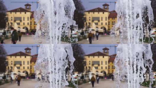 如画的喷泉水喷射到模糊的城镇广场高清在线视频素材下载