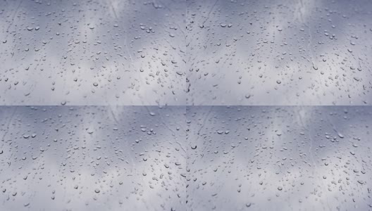 4K的原始视频雨滴落在窗户上，在灰色的天空下特写。高清在线视频素材下载