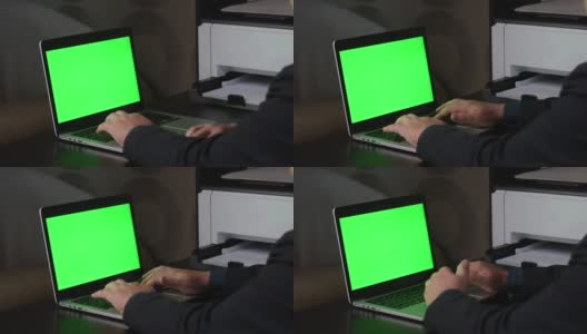 一名男子在一台绿色屏幕的笔记本电脑前工作。竖起大拇指的手势。Chromakey。高清在线视频素材下载