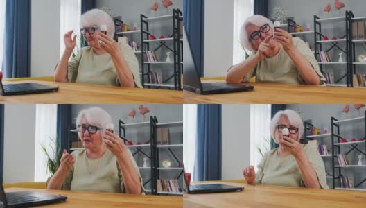 老年妇女边看边用笔记本电脑视频通话，在家在线医疗数字技术服务咨询高清在线视频素材下载