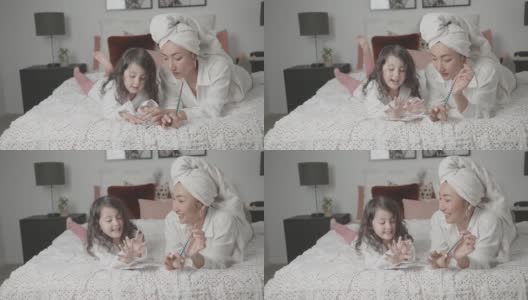 混合亚洲年轻女孩假装玩美甲美容沙龙与她的母亲在床上，家庭生活方式健康的概念高清在线视频素材下载