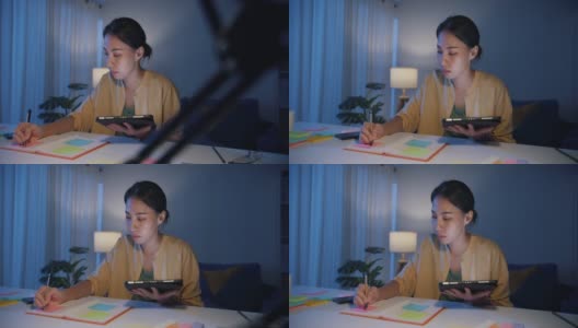 亚洲职业女性，穿着休闲服装，晚上在家客厅用平板电脑工作。高清在线视频素材下载