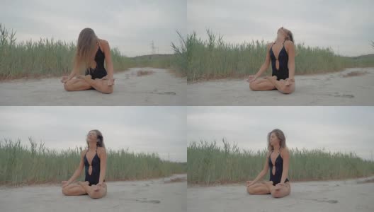 年轻的白人妇女在黑色泳衣放松练习瑜伽在自然附近的芦苇在夏天，近距离的手，吉安mudra和莲花的位置。慢动作高清在线视频素材下载