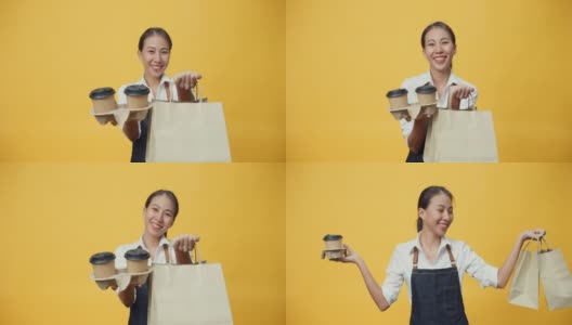 快乐的微笑亚洲女服务员穿着围裙友好地看着镜头给顾客咖啡或茶和美味的食品在手工纸袋隔离在黄色背景。高清在线视频素材下载