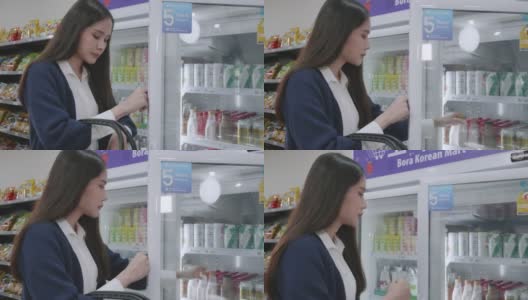 一位妇女在冰箱里选择饮用水，一位亚洲女商人穿着蓝色的休闲装正在购买商品和服务高清在线视频素材下载