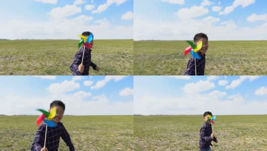 一个亚洲男孩在草原上和风车赛跑高清在线视频素材下载