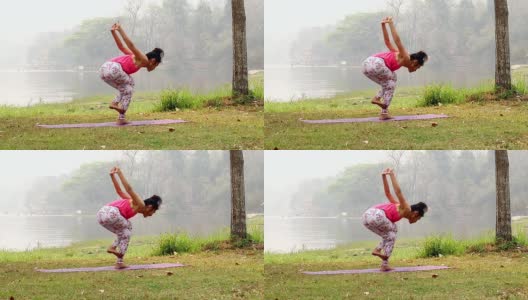 亚洲妇女练习瑜伽做反向鹰姿势在垫子旁边的一个湖在户外公园。高清在线视频素材下载