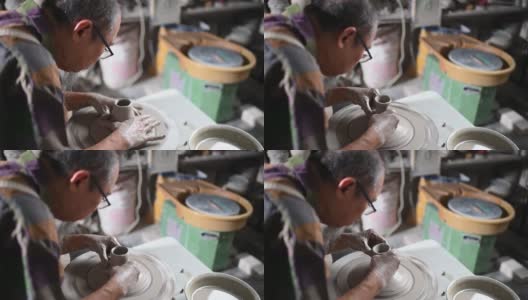 亚洲华人老人与老花泥塑艺术家在他的工作室与纺织陶瓷轮工作高清在线视频素材下载