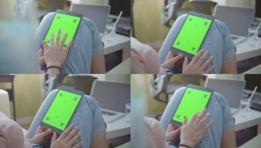 过肩拍摄的女性使用电子平板电脑，绿色屏幕高清在线视频素材下载