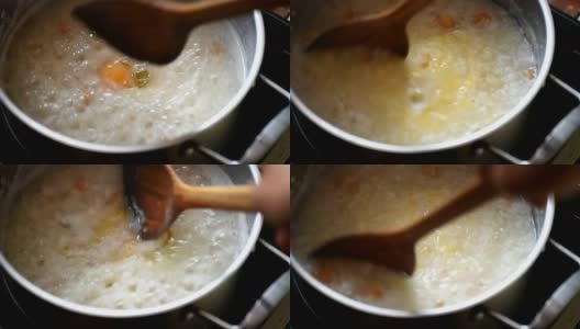在不锈钢锅中加入开水，用木勺将米饭混合高清在线视频素材下载