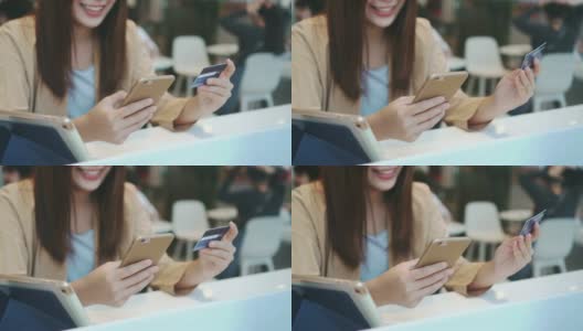 一名亚洲女性使用信用卡和手机进行网上购物的4k视频场景，在百货公司的联合办公空间，技术货币钱包和在线支付概念，信用卡模型高清在线视频素材下载