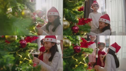一个亚洲少女和她的哥哥姐姐在圣诞节的时候在家里的客厅里装饰圣诞树。高清在线视频素材下载