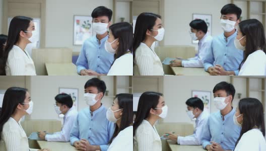 亚洲男性患者戴着医用口罩在现代医院大堂向女医院前台和专业医生询问治疗信息。医院和医疗保健理念。高清在线视频素材下载