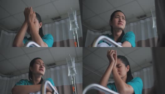 一位身着医院长袍的亚洲妇女闭上眼睛，独自在医院的床上哭泣。她又沮丧又担心。高清在线视频素材下载