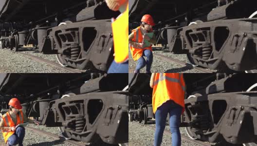 一位年轻的女铁路工人正在检查货车的悬挂装置。高清在线视频素材下载