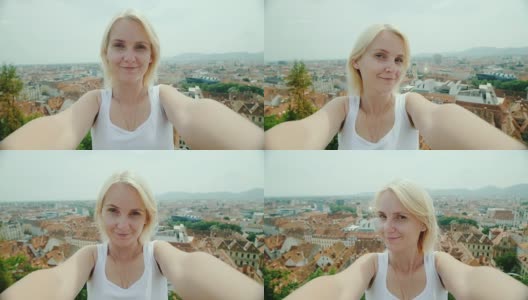奥地利格拉茨，一名年轻女子在城市空间的映衬下自拍。欧洲城市的旅游业高清在线视频素材下载