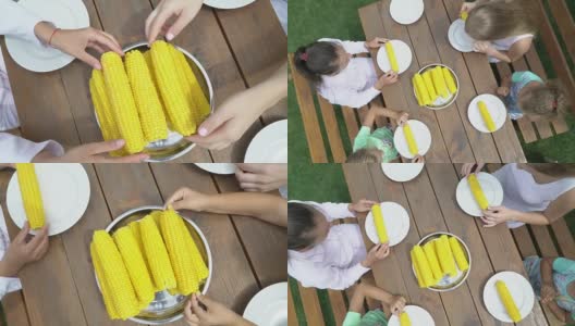在花园里举行家庭吃玉米比赛。孩子们开心地吃着甜玉米芯高清在线视频素材下载