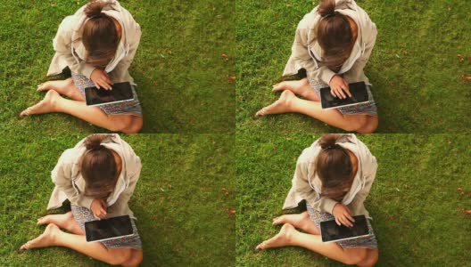 学生坐在草坪上用平板电脑工作高清在线视频素材下载