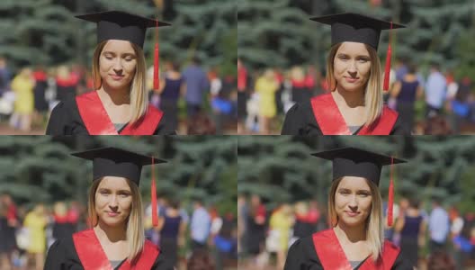 美丽的年轻女子在学术服装看着相机，成功的毕业生高清在线视频素材下载