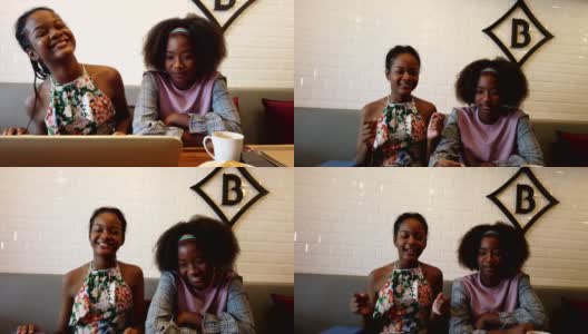美丽的女孩半亚裔非洲人看笔记本社交媒体，音乐，电影，感觉幸福的早晨聚集在咖啡馆。高清在线视频素材下载