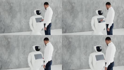 一个时髦的男人与机器人交流，向机器人按一个塑料机械臂，握手。今天控制论系统。现代机器人技术。仿人机器人自主高清在线视频素材下载