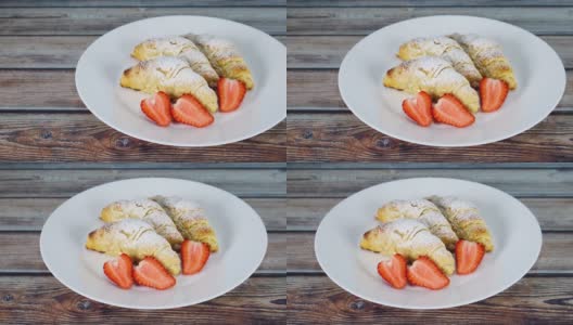 白砂糖和草莓片的甜羊角面包装在白色的盘子里高清在线视频素材下载