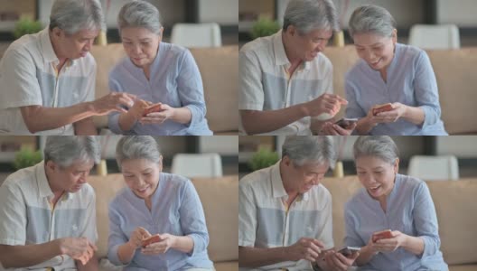 亚洲华人老年夫妇在周末休闲时间在客厅学习使用智能手机高清在线视频素材下载