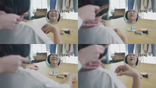 有魅力的年轻老年亚洲女性公民开心的脸在早上与护士在家例行生活方式，头发刷梳头，亚洲护理在家照顾志愿者，协助生活的服务理念。高清在线视频素材下载