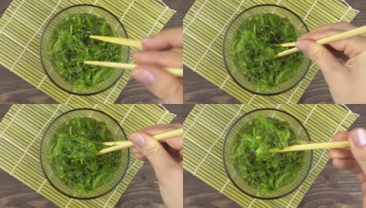 一名妇女用筷子夹起丘卡海带。玻璃碗里的丘卡海草，4k高清在线视频素材下载