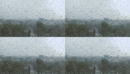 雨点在窗户上的缓慢运动与模糊的背景，雨天，玻璃上的水滴，感觉孤独和悲伤的概念。坏天气的一天。透过窗户看风景高清在线视频素材下载