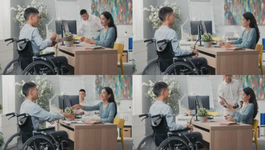 男人们坐在轮椅上坐在办公室的桌子前，对面是一个穿着裙子的漂亮女人，一个同事带来一份他们签署的合作合同，他们互相感谢对方的面试高清在线视频素材下载