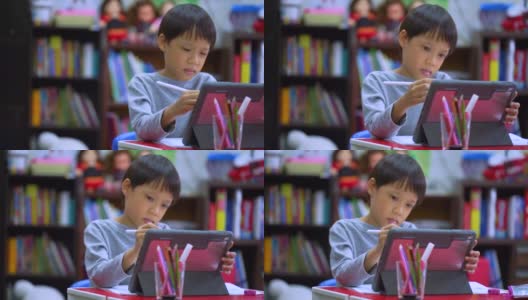 在线教育的概念。在线课堂。亚洲小男孩在家学习。孩子在家里的客厅里用数码平板画画。高清在线视频素材下载