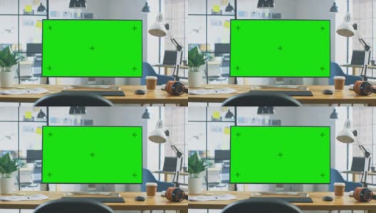 在现代创意办公室的桌子上站立的绿色宽模型桌面电脑。在背景明亮的创意Loft为开发商和设计师的专业工作高清在线视频素材下载