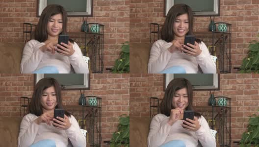 年轻漂亮的亚洲女人在沙发上玩手机高清在线视频素材下载