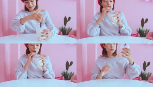 年轻的亚洲千禧一代女性在粉色柔和的咖啡馆喝冰珍珠奶茶高清在线视频素材下载